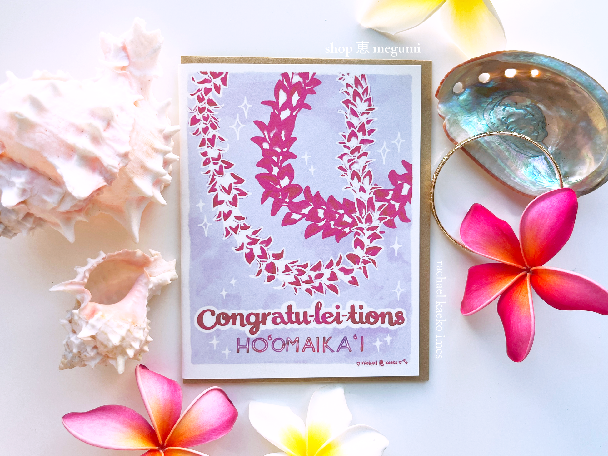Hawaii-style greeting card that reads "Congratu-lei-tions" and "Ho'omaika'i" with floral design and text, surrounded by flowers and seashells on a light background.