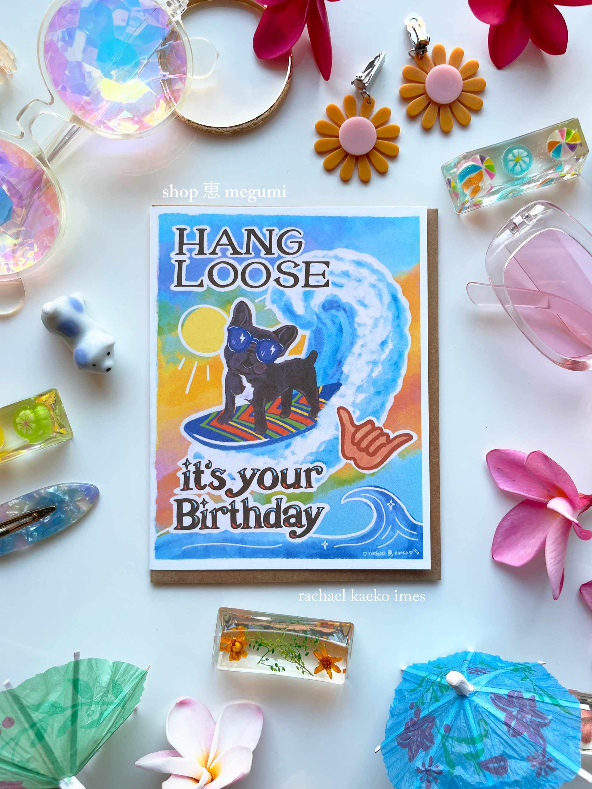 Birthday card with a dog surfing design surrounded by decorative items on a white background