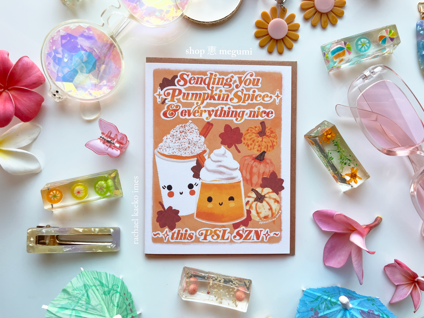 Autumn-themed greeting card with cute pumpkin spice latte illustration design and "PSL SZN" text surrounded by decorative items on a white background