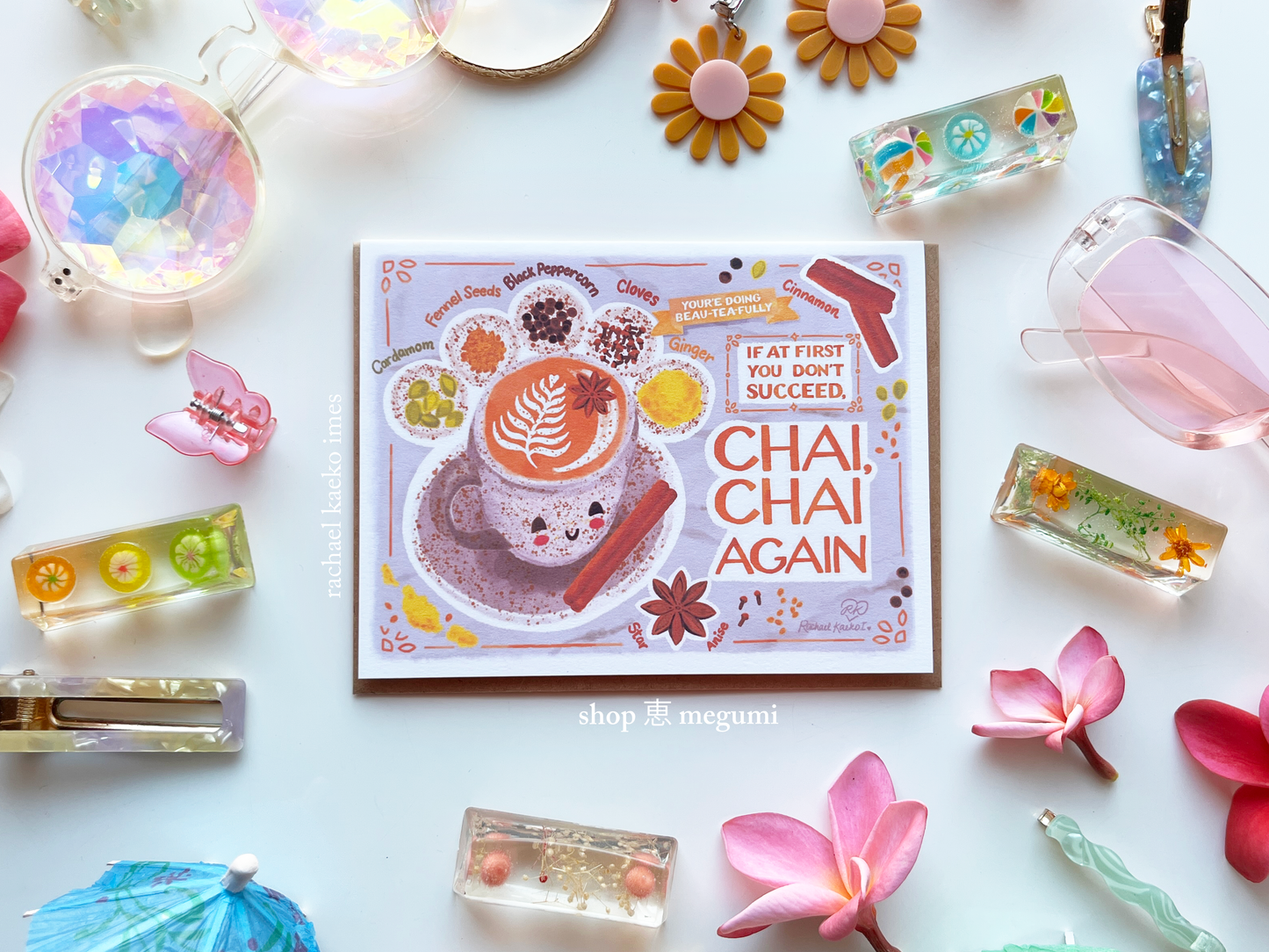 Kawaii chai tea greeting card with a chai latte art and text that says 'Chai, Chai Again' surrounded by decorative items on a white background.