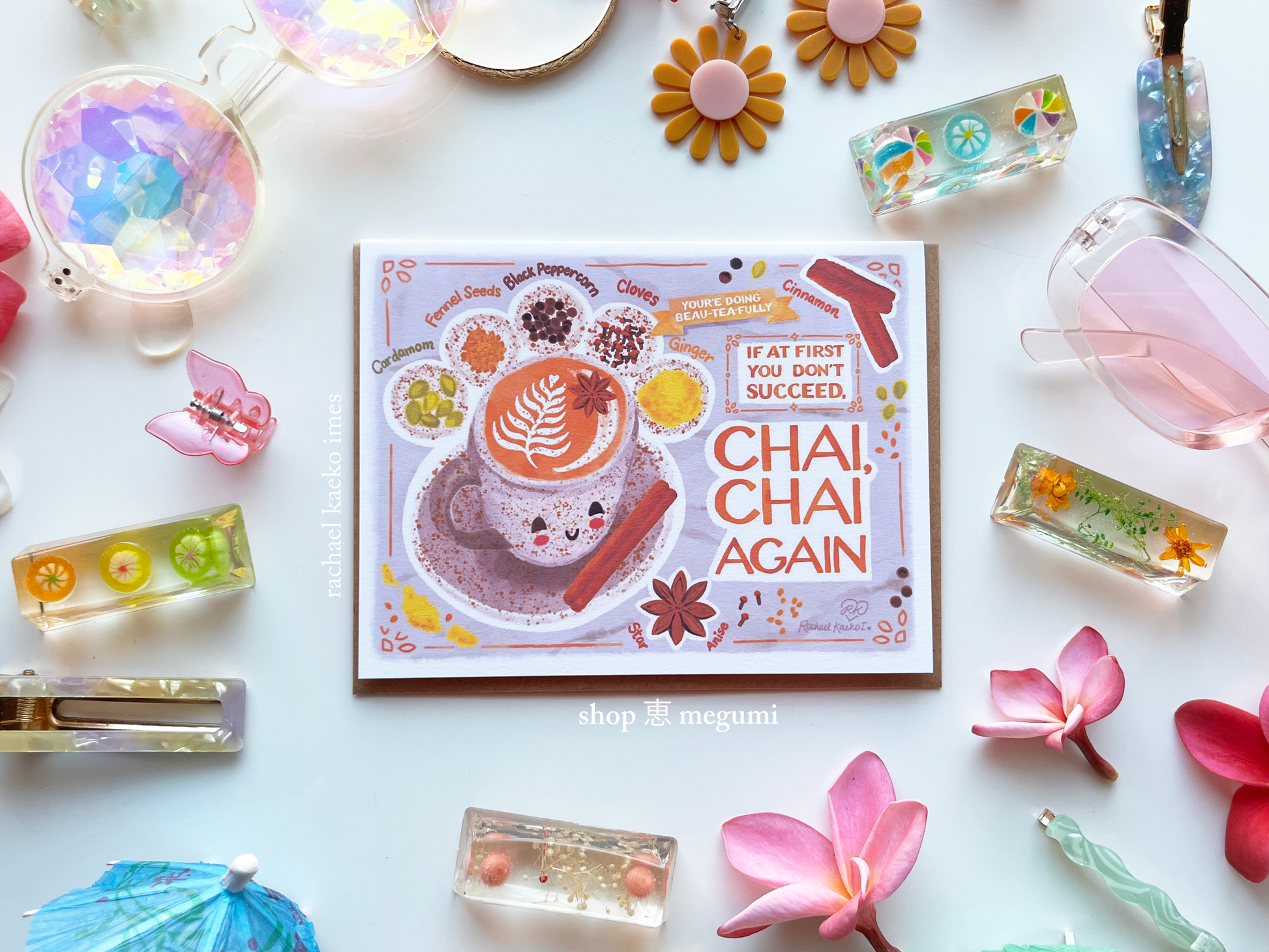 Kawaii chai tea greeting card with a chai latte art and text that says 'Chai, Chai Again' surrounded by decorative items on a white background.