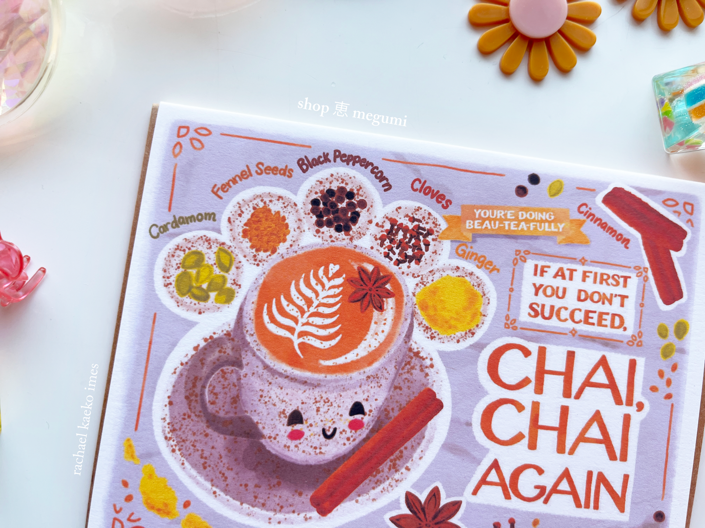 Close-up of an illustrated greeting card with a design of a chai tea cup with a smiling face and text on a white background