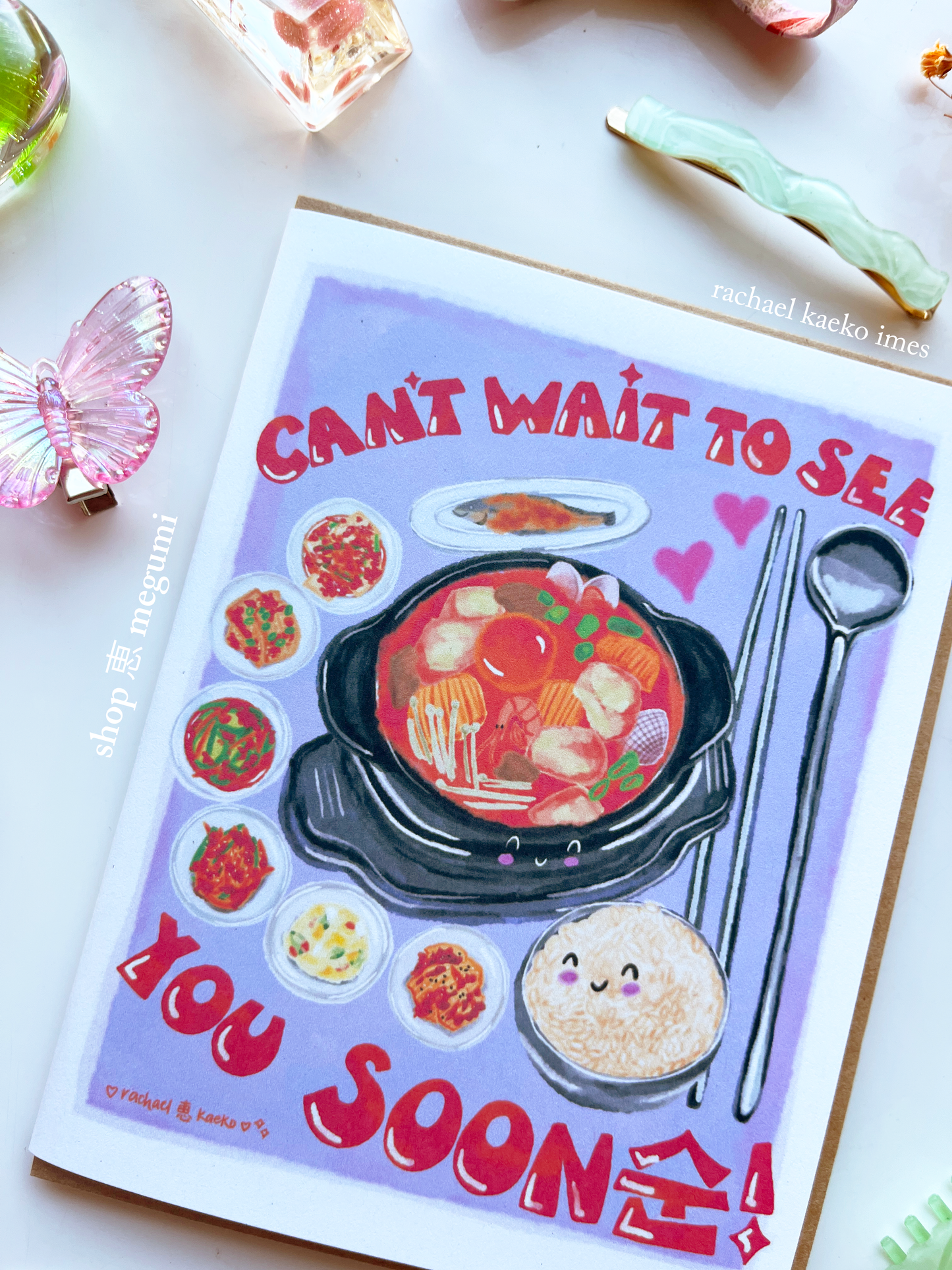 Cute Korean food greeting card with food illustrations and text 'Can't wait to see you soon' on a white surface.