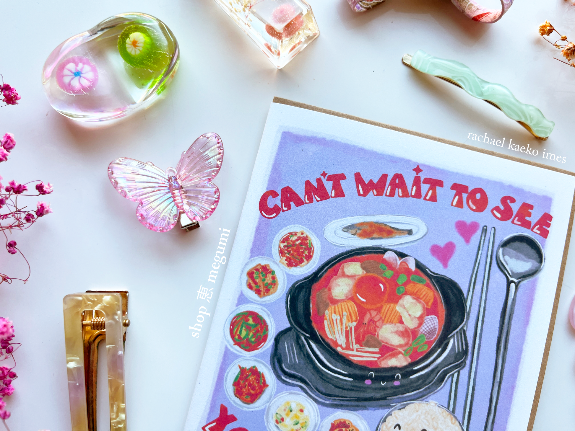 Korean food illustrated greeting card with Korean banchan illustrations and text on a white surface with decorative items.