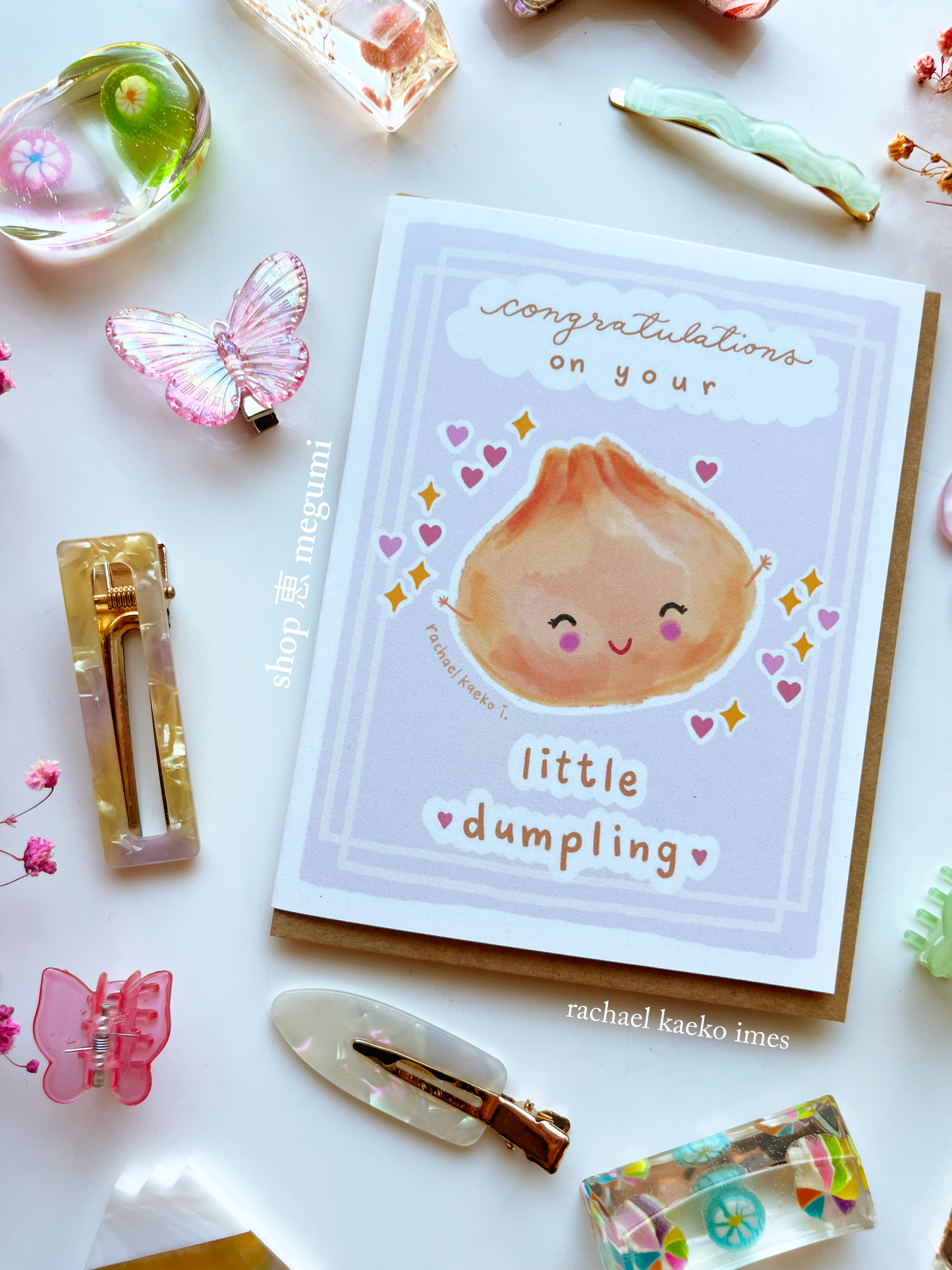 Cute baby shower greeting card with a cute illustration of a dumpling and text 'Congratulations on your little dumpling' on a decorative background.