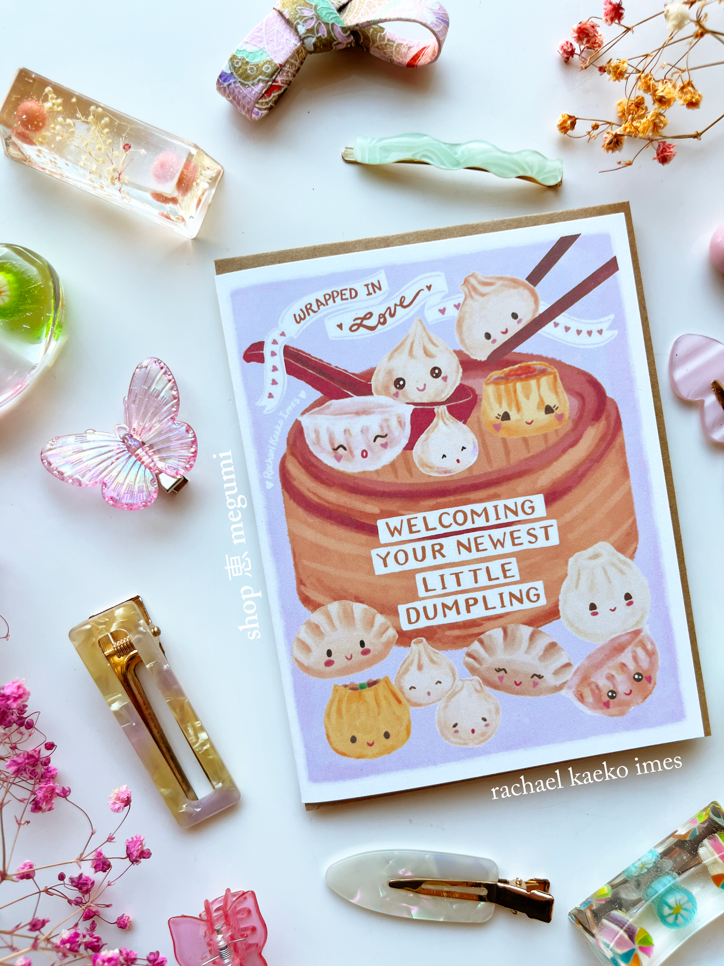 Dumpling baby shower card with kawaii dumpling illustrations surrounded by decorative items on a white background