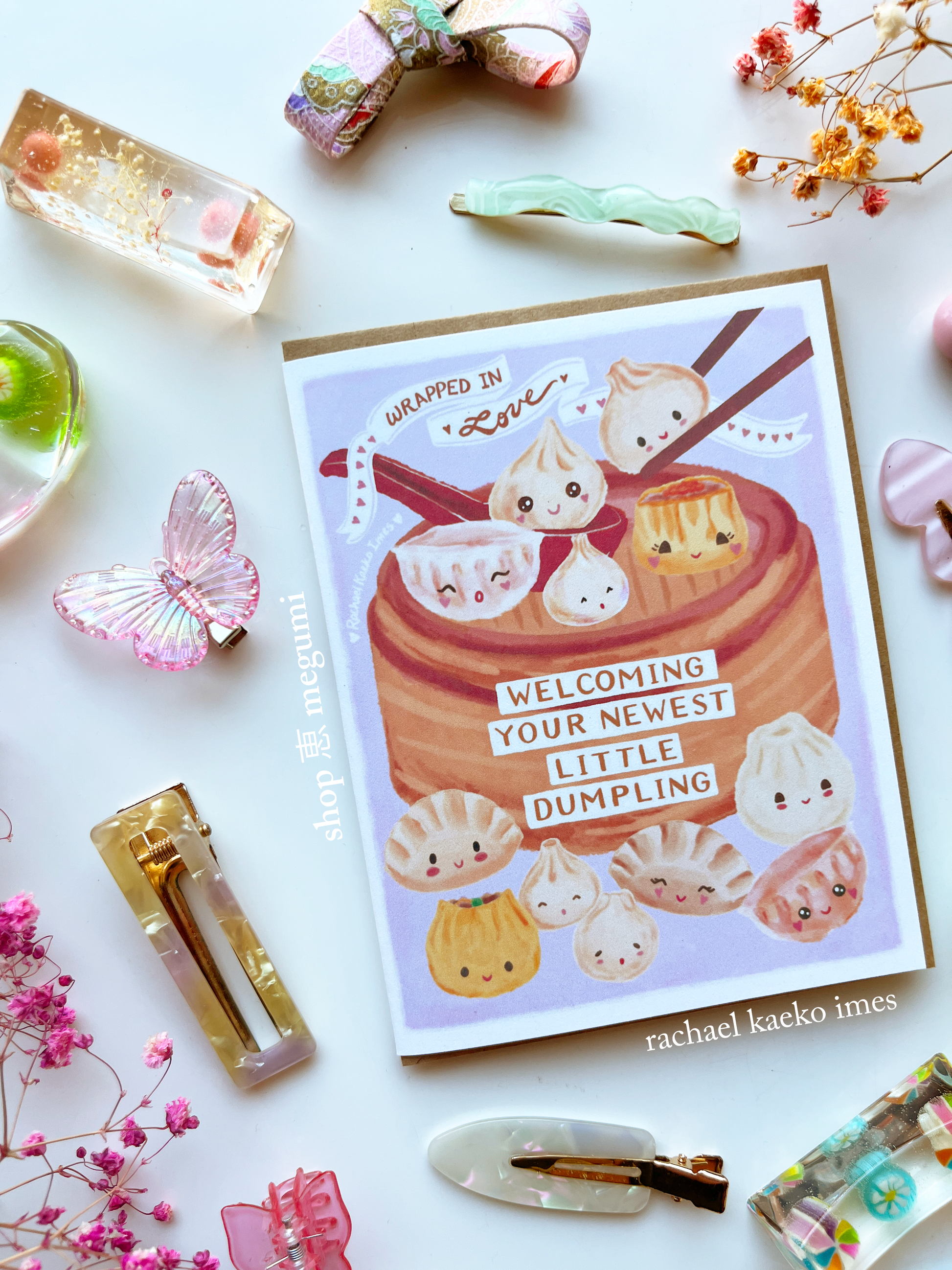 Dumpling baby shower card with kawaii dumpling illustrations surrounded by decorative items on a white background