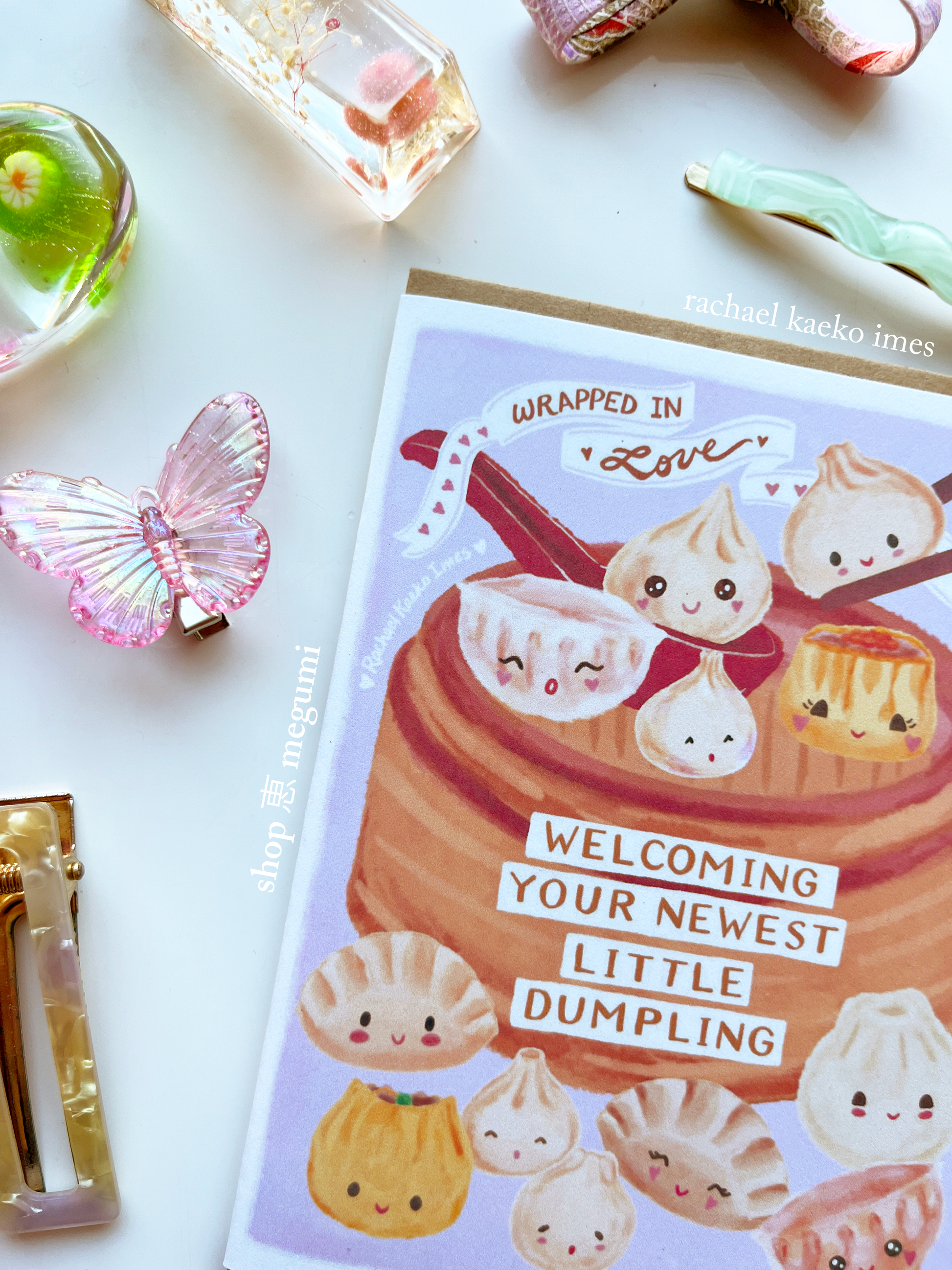 Close-up of Asian dumpling greeting card with cute dumpling illustrations and text on a white surface with decorative items.
