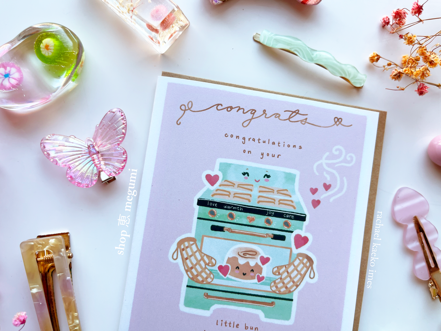 Cute baby congrats card with little bun-themed illustration on a white surface with decorative items.