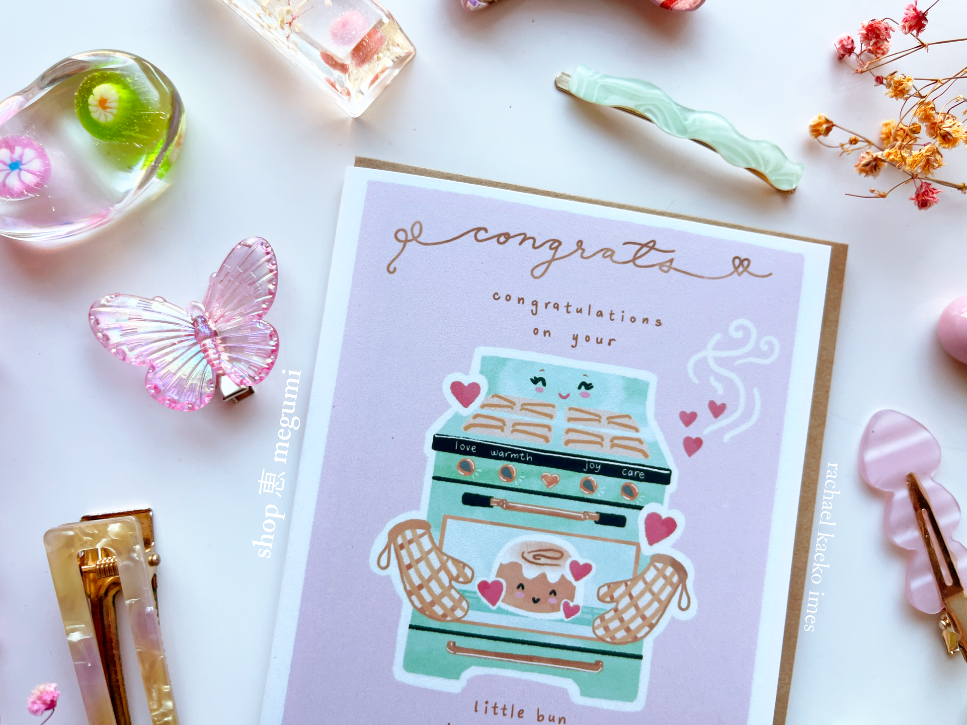 Cute baby congrats card with little bun-themed illustration on a white surface with decorative items.