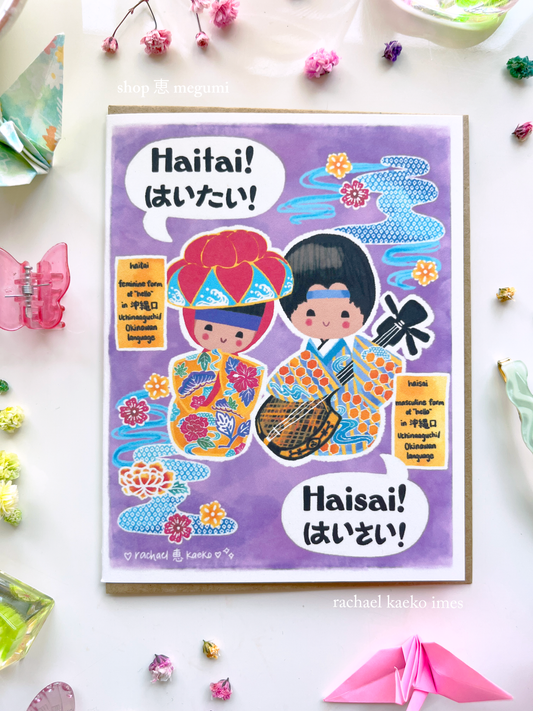 Colorful Okinawa-inspired greeting card with Japanese and English text that reads "Haitai! Haisai!" and illustrations of Okinawa kokeshi dolls, on a white background.