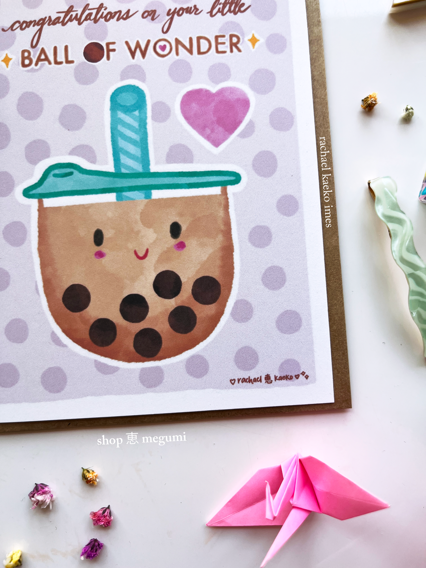 Card with a cute illustration of a bubble tea and text 'Congratulations on your little ball of wonder' on a polka dot background.